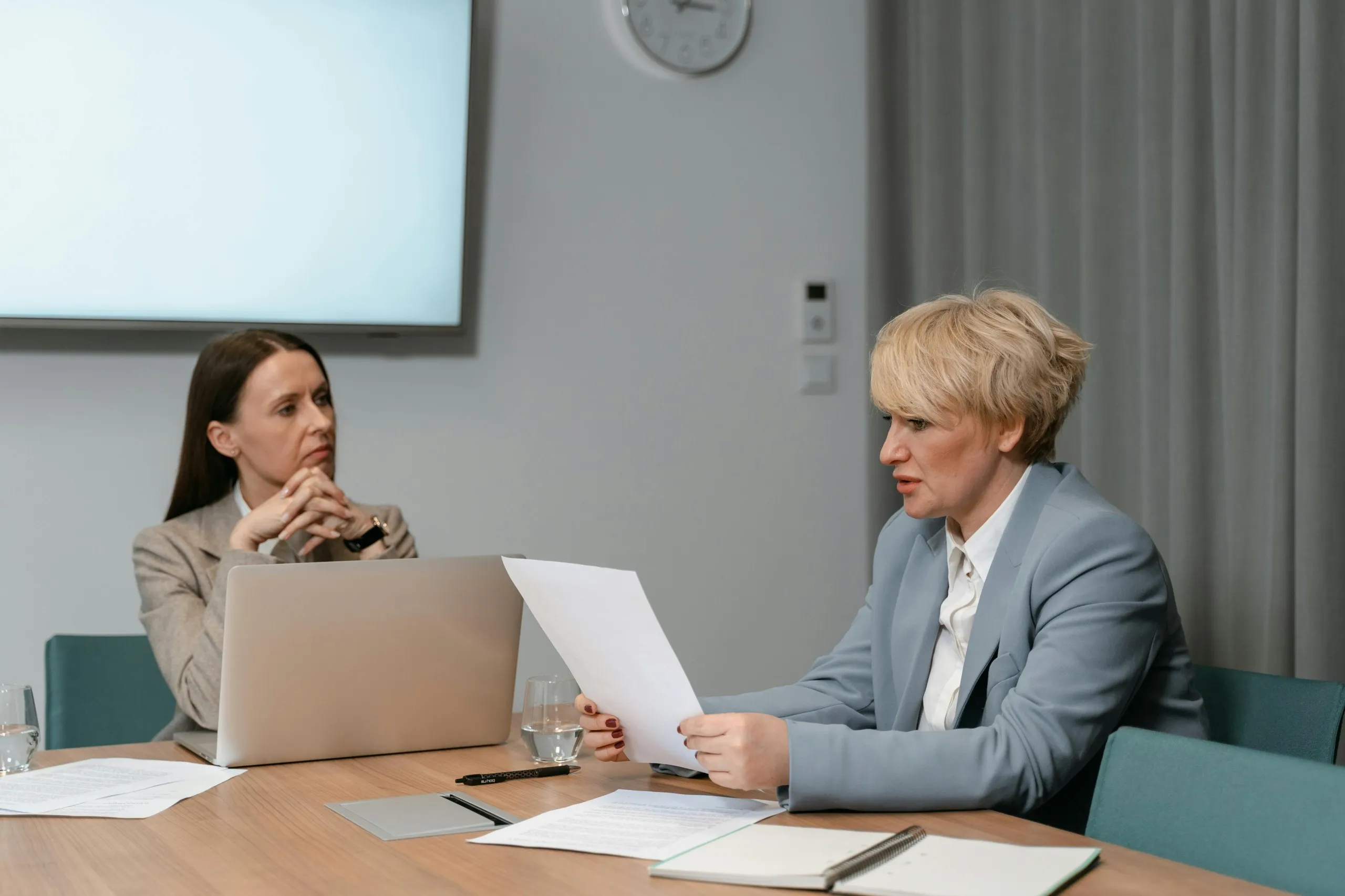 Two business professionals in a meeting discussing documents, representing clear communication with a remote executive assistant handling acquisition tasks.