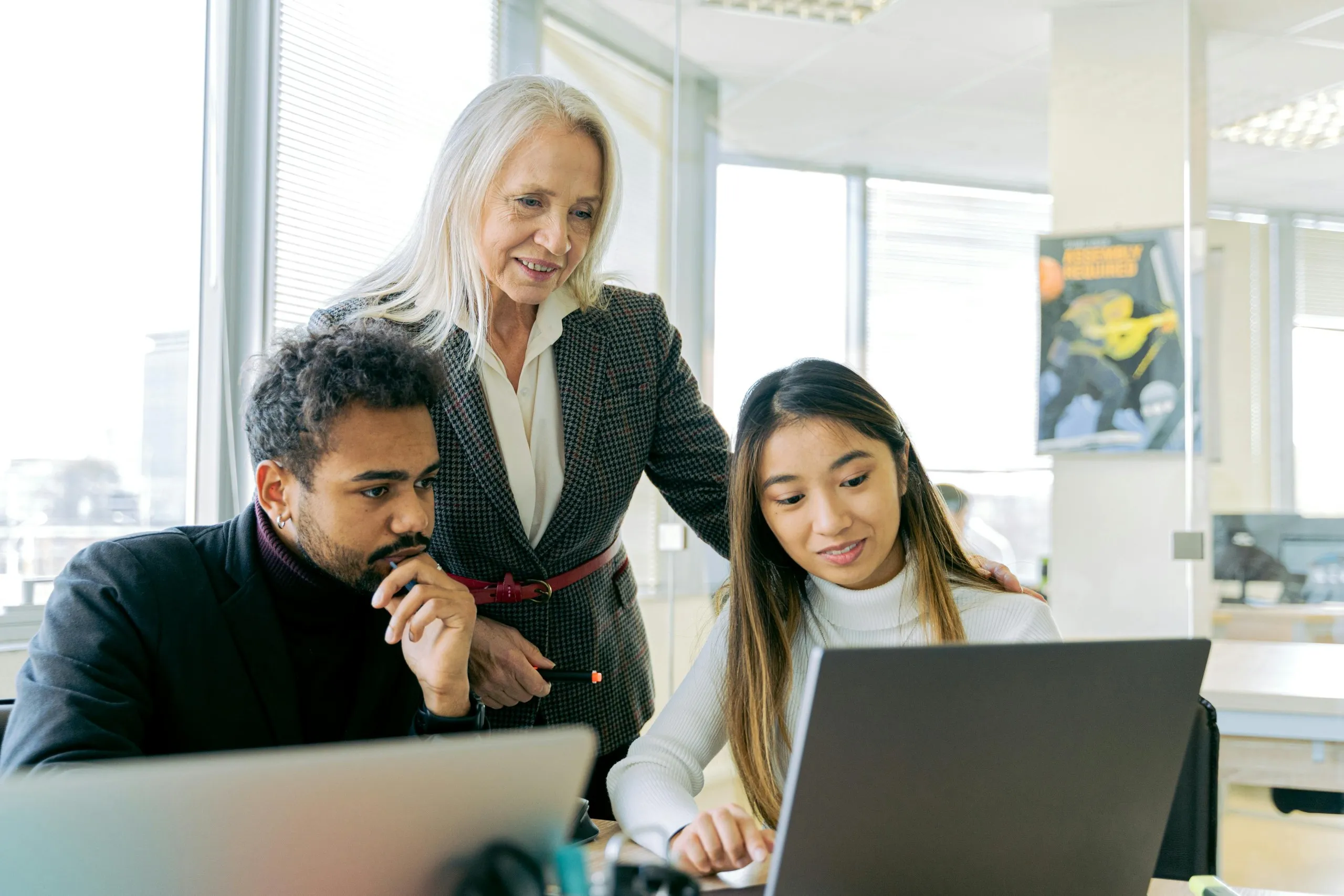 Coworkers discussing tasks with a laptop and planning tools, highlighting delegation of SMM duties to a virtual executive assistant.