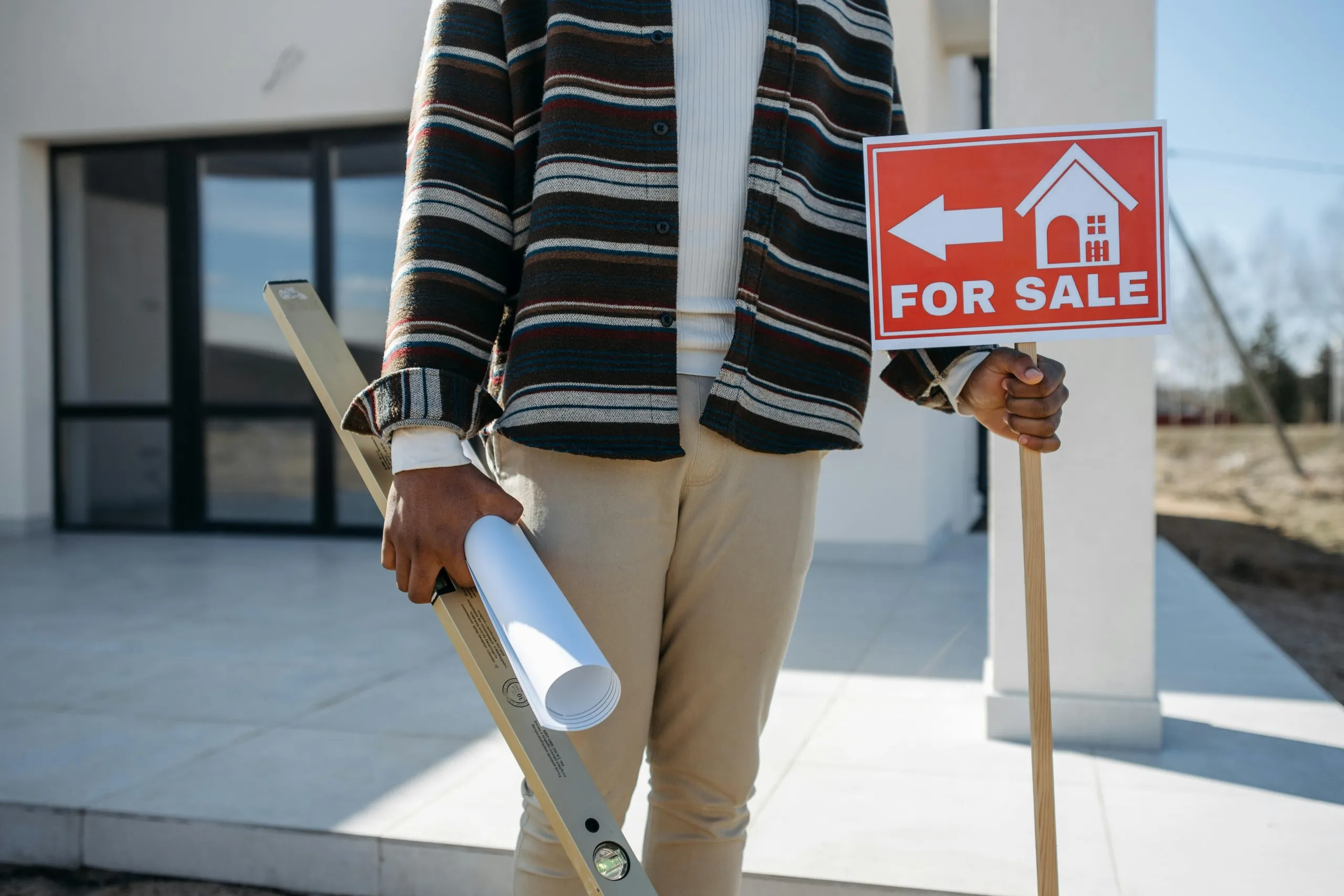 Person showcasing property management materials and a 'For Sale' sign, representing the role of a virtual executive assistant in real estate support.