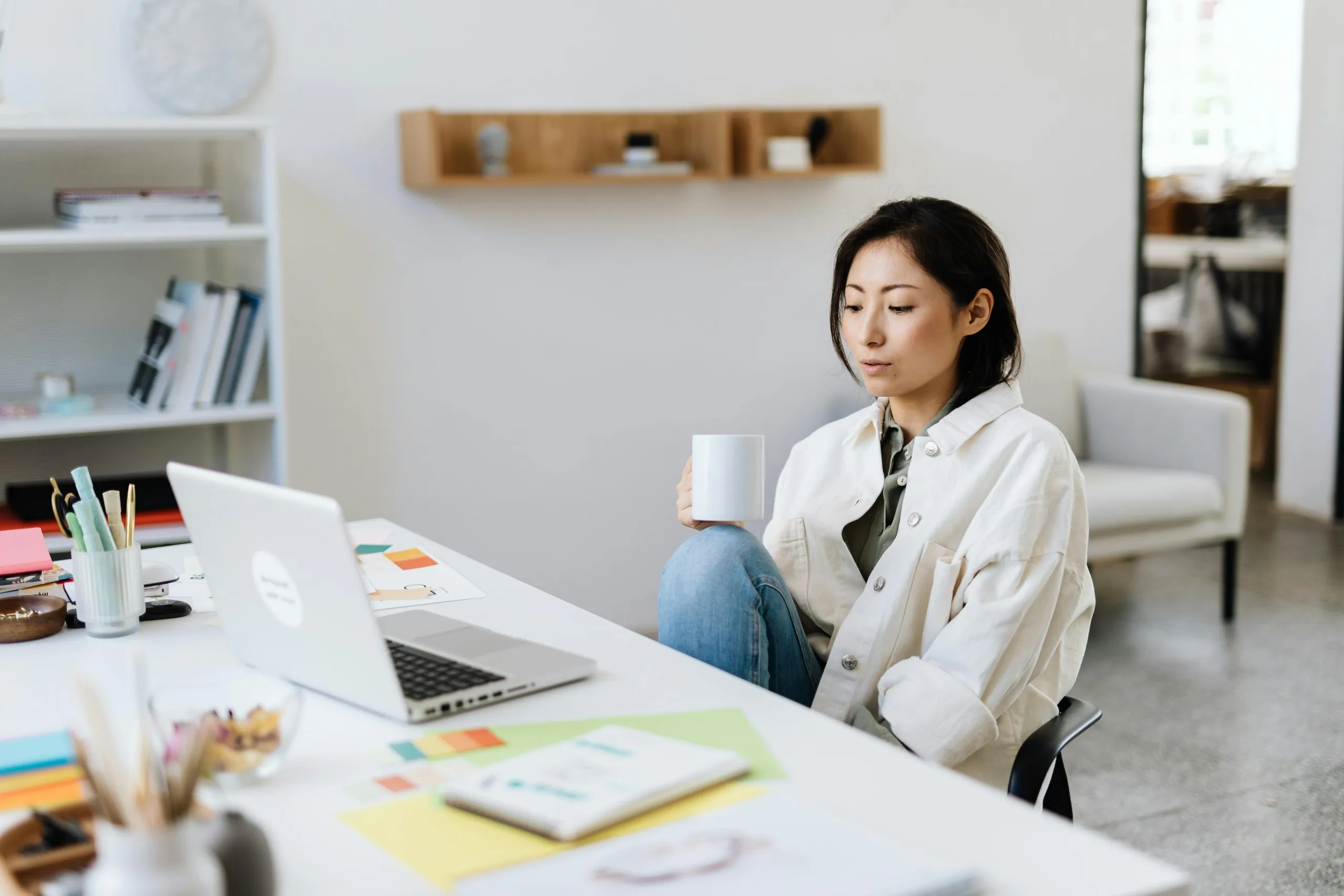 Woman working on a laptop at a clean desk with coffee, planner, and organizing tools, representing a remote executive assistant.