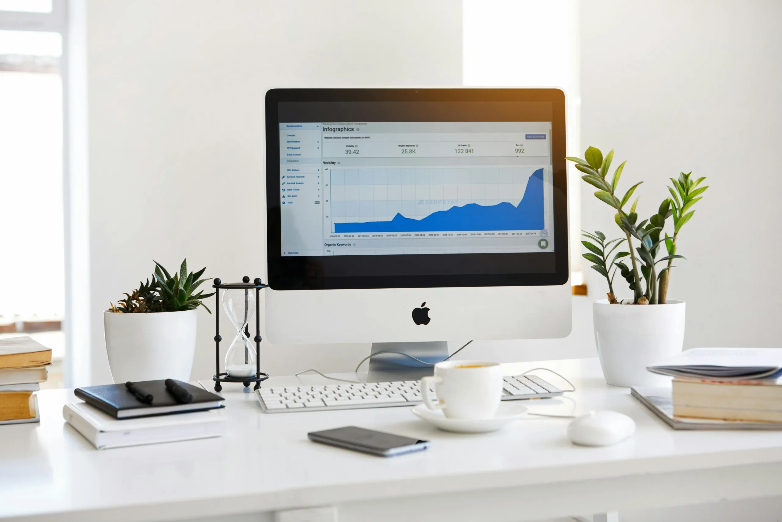Desktop computer on a minimalist desk displaying keyword analytics and growth charts, illustrating a productive setup for content development, strategic planning, and performance tracking by modern digital creators.